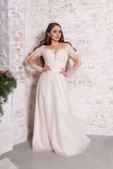 Fototapeta premium Bride in a white dress against a brick wall.