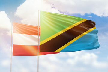 Sunny blue sky and flags of tanzania and austria