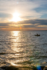 Obraz premium A lone boat floats on Lake Nippising as its rider enjoys the beautifully colour sunset in North Bay, Ontario.