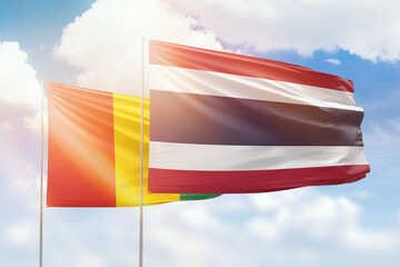 Sunny blue sky and flags of thailand and guinea
