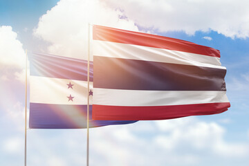 Sunny blue sky and flags of thailand and honduras