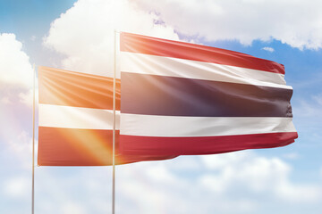 Sunny blue sky and flags of thailand and latvia
