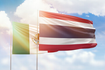 Sunny blue sky and flags of thailand and mexico