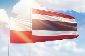 Sunny blue sky and flags of thailand and poland