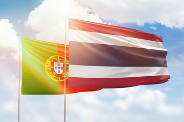 Sunny blue sky and flags of thailand and portugal