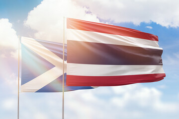 Sunny blue sky and flags of thailand and scotland