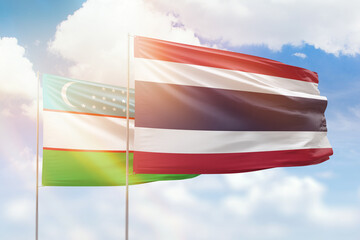 Sunny blue sky and flags of thailand and uzbekistan