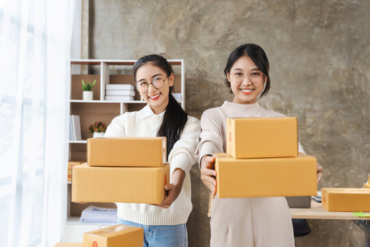 Looking At Camera,Partnership Of SME Entrepreneur Teamwork Of Small Business Work At Home Family Online Marketing With Packing Box Prepare For Deliverty To Customers At Warehouse Home Seller Office.