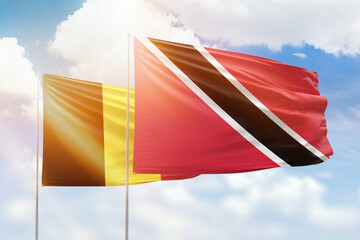 Sunny blue sky and flags of trinidad and tobago and belgium