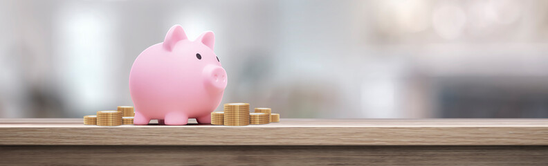 Pink piggy bank with coins on a wooden table - savings concept
