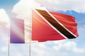 Sunny blue sky and flags of trinidad and tobago and france