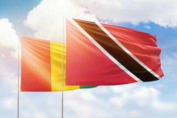 Sunny blue sky and flags of trinidad and tobago and guinea
