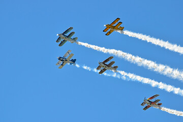 Biplanes at an airshow release smoke trails as they get ready to do their stunts.