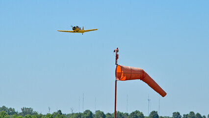 An AT-6 takes off in the direction indicated by a windsock.