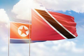 Sunny blue sky and flags of trinidad and tobago and north korea