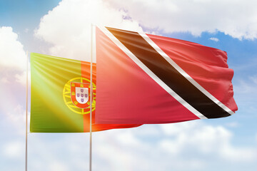 Sunny blue sky and flags of trinidad and tobago and portugal