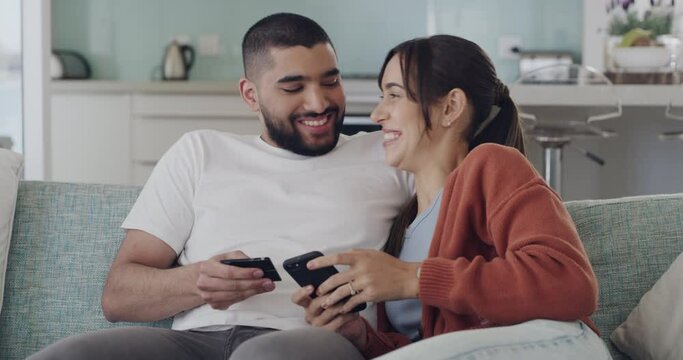 Young cheerful mixed race couple using a phone and credit card and phone together at home. Joyful boyfriend and girlfriend making an online purchase with a debit card and cellphone
