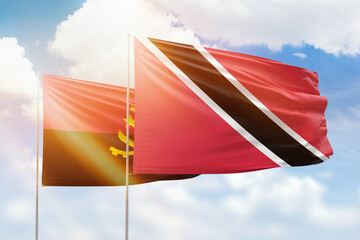 Sunny blue sky and flags of trinidad and tobago and angola