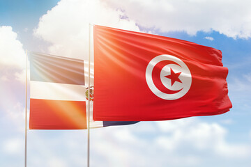 Sunny blue sky and flags of tunisia and dominican republic