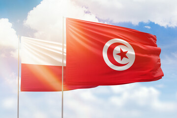 Sunny blue sky and flags of tunisia and poland