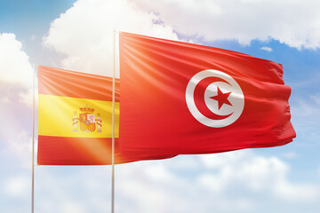 Sunny blue sky and flags of tunisia and spain