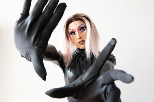 lgbtiq drag queen posing for the camera in a black latex and leather outfit looking to the side. High quality photo