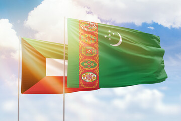 Sunny blue sky and flags of turkmenistan and kuwait