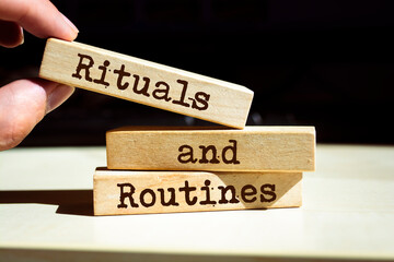 Businessman puts wooden blocks with the words rituals and routines.