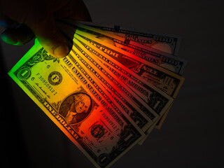 Rays of a rainbow on a man's hand with a bundle of dollars. 