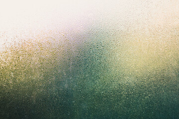 water droplets of humidity condensation on window glass seen from indoor with backyard bokeh in the background - obrazy, fototapety, plakaty