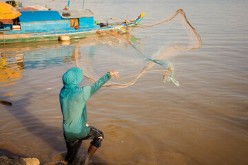 Fisherman using net to catch fishes