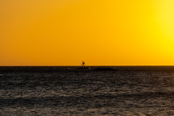 Beautiful view of an orange sunset in the midel of the Costa Rica Ocean, with a boat and pelicans 