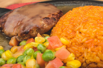 Salisbury Steak, served with mixed vegetables and fried java rice on a sizzling plate with gravy.
