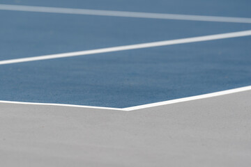 Blue tennis court with white lines and gray out of bounds	