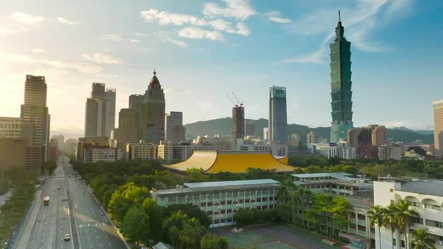 Cinematic aerial shot showing Sun Yat-Sen Memorial Hall and silhouette of skyscraper towers in Taipei City during sunset