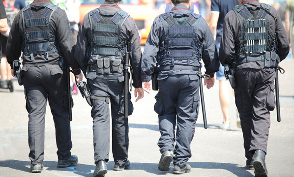 patrols of four policemen in riot gear with flak jackets and batons while watching the riot