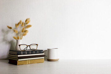 Books, with glasses, coffee cup and natural flower over the table with natural light.