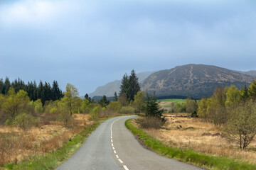 Scenice landscape view of a highway traveling through a rural Scottish countryside, with trees and hills in the background
