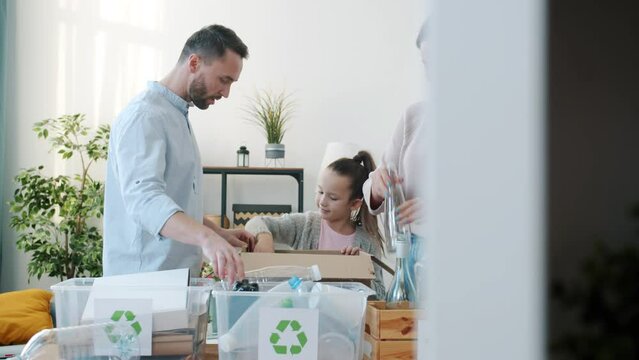 Child helping young responsible parents with sorting rubbish putting plastic and bottles in containers at home. Zero waste and family lifestyle concept.