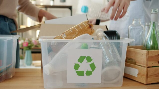 Close-up of recycling containers and hands male and female sorting out garbage at home. Environment protection and zero waste concept.