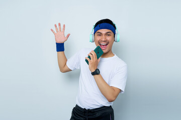 Cheerful young Asian man sporty fitness trainer instructor in blue headband and white t-shirt with...