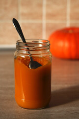baby pumpkin puree in a glass jar with a spoon and fresh pumpkin