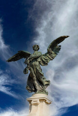 Fototapeta premium Rome, Italy - June 2000: Statue of an angel with outstretched wings against a blue sky background