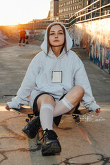 Shot of female skater dressed in white stylish hoody hairs at skate park. © Fxquadro