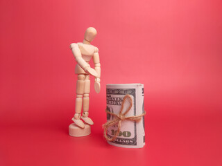 Wooden mannequin and banknotes on a red background.
