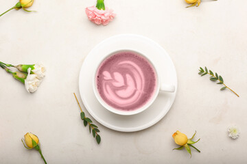 Cup of pink matcha tea with beautiful spring flowers on light background