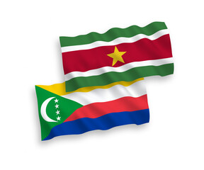 National vector fabric wave flags of Union of the Comoros and Republic of Suriname isolated on white background. 1 to 2 proportion.