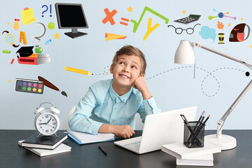 Cute little boy doing homework at table against light background