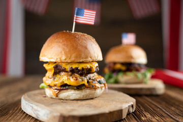 Fourth of July celebration. American flag and decorations. Burgers on rustic wooden table.