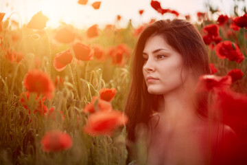 Portrait of a woman in the poppy field against strong sunlight